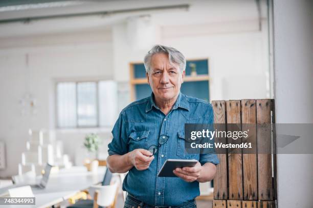 portrait of senior businessman holding tablet in office - old man looking at camera stock pictures, royalty-free photos & images
