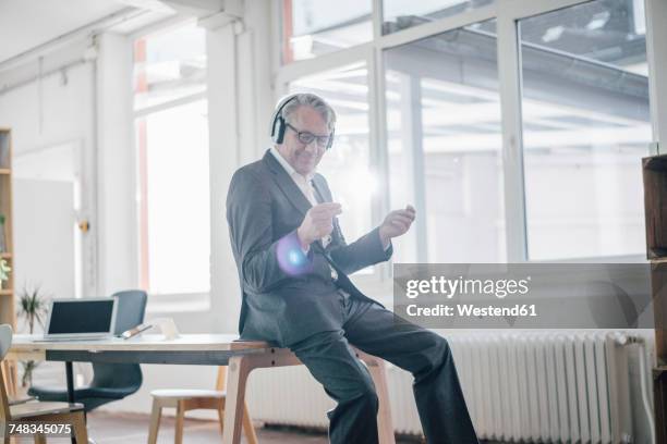 happy senior businessman listening to music with headphones in office - met de vingers knippen stockfoto's en -beelden