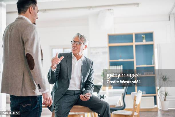 senior businessman talking to young businessman in office - strict parent fotografías e imágenes de stock