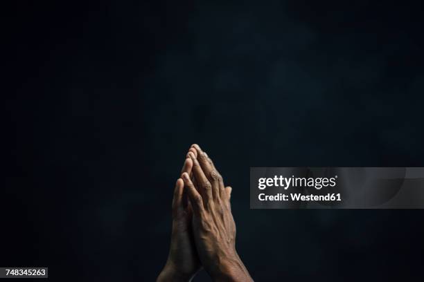 hands of man and black background - black spirituality stock pictures, royalty-free photos & images