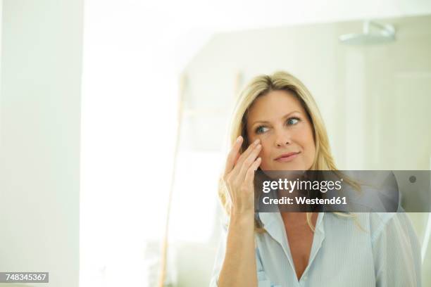 portrait of woman looking at her mirror image in the morning - mature woman beauty stock pictures, royalty-free photos & images