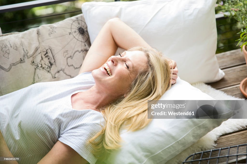 Laughing blond woman relaxing on balcony
