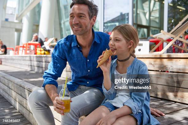 Father with drink and daughter with ice cream cone at an outdoor cafe