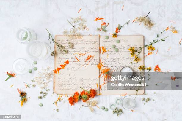 dried medical plants and globuli on old recipe book - calendula stockfoto's en -beelden