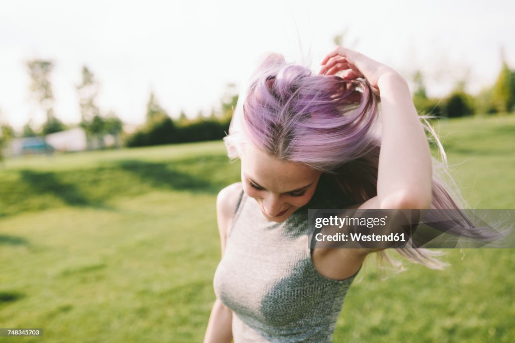 Young woman with pink grey hair dancing on a meadow