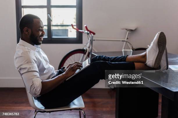 man using laptop in home office with feet on desk - feet up stock pictures, royalty-free photos & images