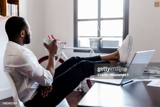 relaxed man in home office with feet on desk - feet on table bildbanksfoton och bilder