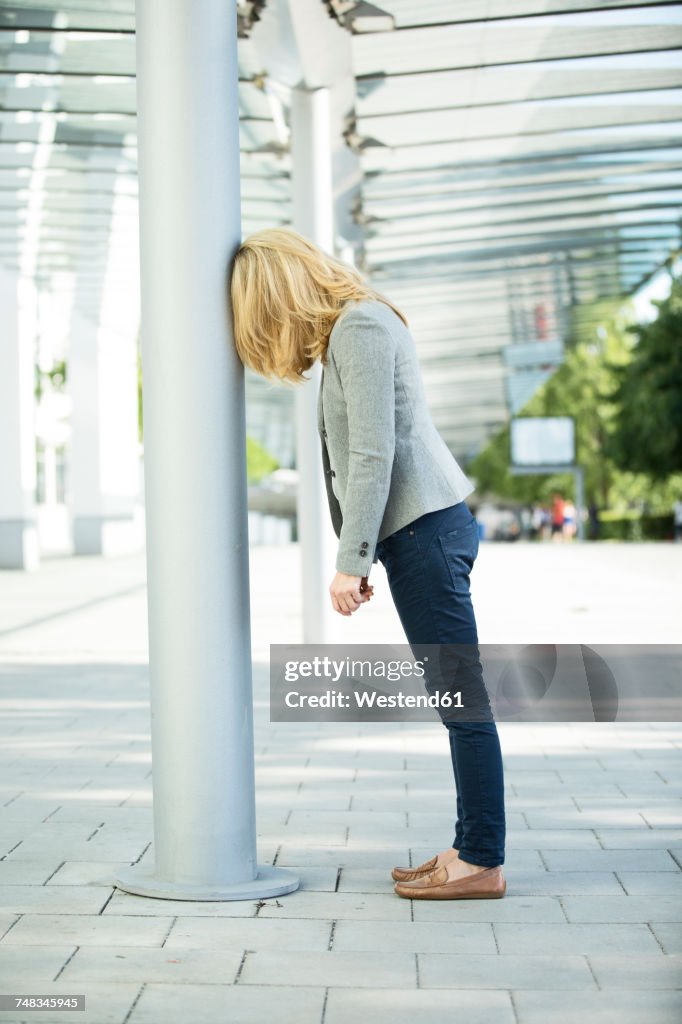 Frustated woman leaning against column