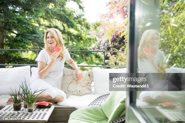 mature woman sitting on balcony, eating water melon - endast en medelålders kvinna bildbanksfoton och bilder