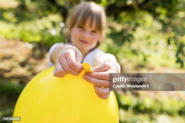 girl holding balloon on meadow - inflate stockfoto's en -beelden