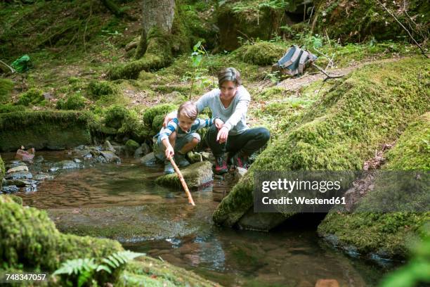 mother and little son crouching at edge of a brook - monbach stock pictures, royalty-free photos & images