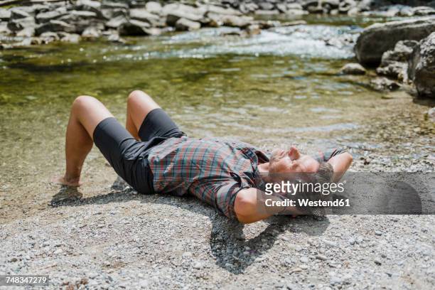 hiker having a break at the riverbank - hände hinter dem kopf stock-fotos und bilder