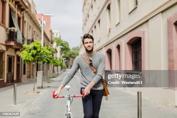 young man pushing his bike - walking with bike stock-fotos und bilder