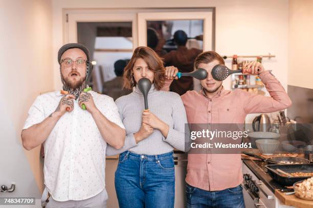 group picture of three friends having fun with kitchen utensils - portrait department store stockfoto's en -beelden