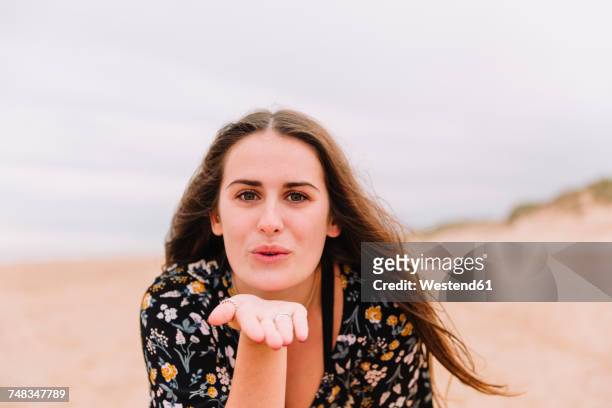 portrait of young woman blowing kiss on the beach - blowing a kiss stockfoto's en -beelden