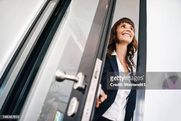 businesswoman opening glass door - vorstellen stock-fotos und bilder