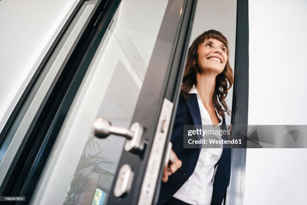 Businesswoman opening glass door