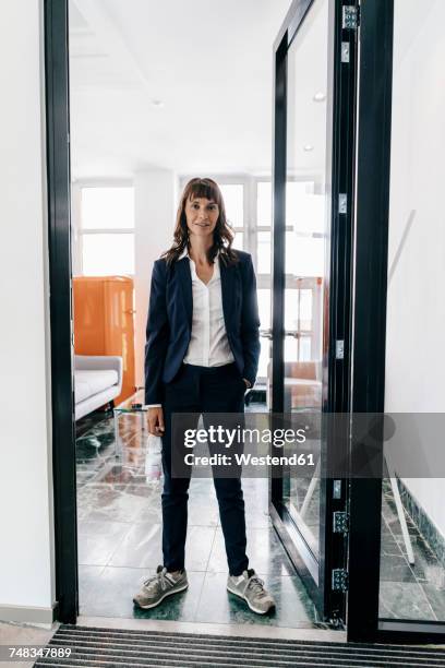 businesswoman wearing trainers, standing in open door - pre reception stockfoto's en -beelden