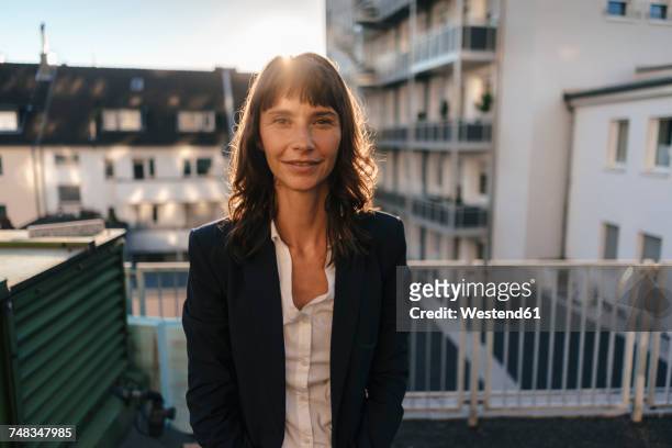 businesswoman staanding on balcony enjoying the sunshine - backlit portrait stock pictures, royalty-free photos & images