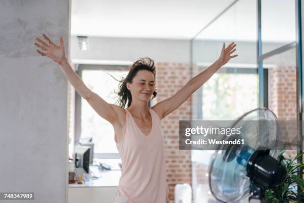 businesswoman in office enjoying breeze from a fan - heat temperature 個照片及圖片檔