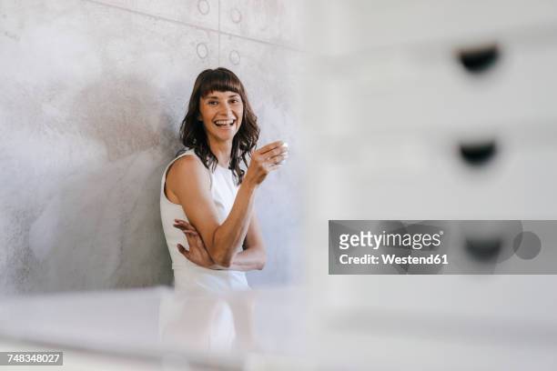 woman drinking coffee in office, leaning against wall - focus on background stock pictures, royalty-free photos & images