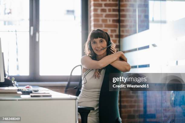 woman sitting in office, wearing headset - call center stock-fotos und bilder