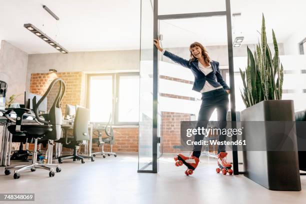 successful businesswoman wearing roller skates in office - skate sports footwear stock-fotos und bilder