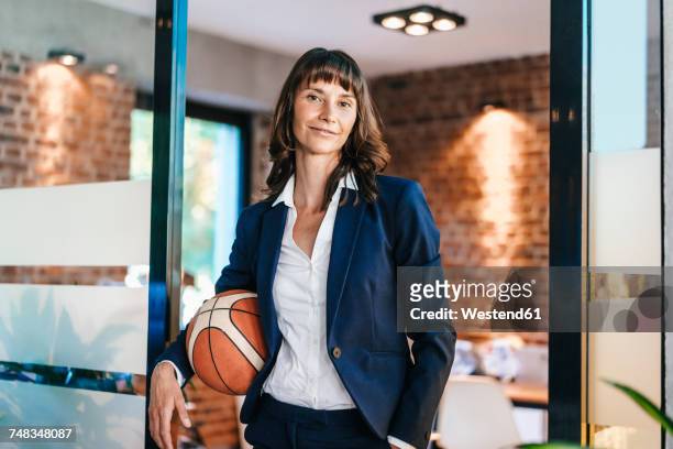 businesswoman holding basket ball in office - basketball sport stock-fotos und bilder