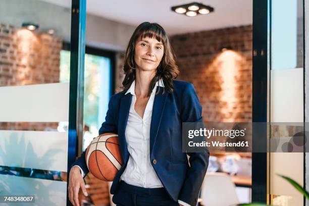 businesswoman holding basket ball in office - leisure equipment fotografías e imágenes de stock