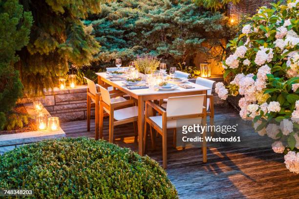 laid table on lighted terrace - lanterns stock-fotos und bilder
