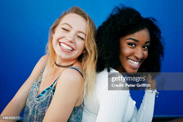 friends sitting near blue wall laughing - ritratto coppia mista foto e immagini stock