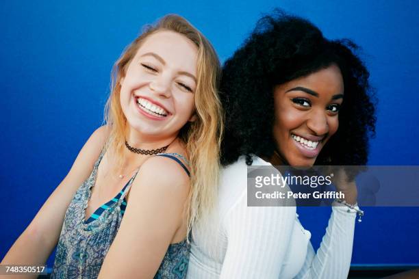 friends sitting near blue wall laughing - 2 people smiling stock pictures, royalty-free photos & images