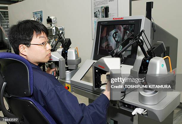 An engineer sits on the remote control unit of the HRP-3 Promet Mk-II humanoid robot during its press preview at Kawada industry's laboratory in Haga...