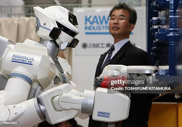Kawada Industry's humanoid robot project leader Takakatsu Isozumi explains speaks next to a HRP-3 Promet Mk-II humanoid robot during its press...