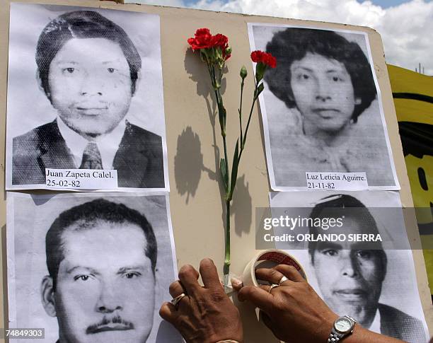 Guatemala City, GUATEMALA: Una mujer coloca claveles en un mural con fotos de victimas del conflicto armado en Guatemala al conmemorarse el Dia...