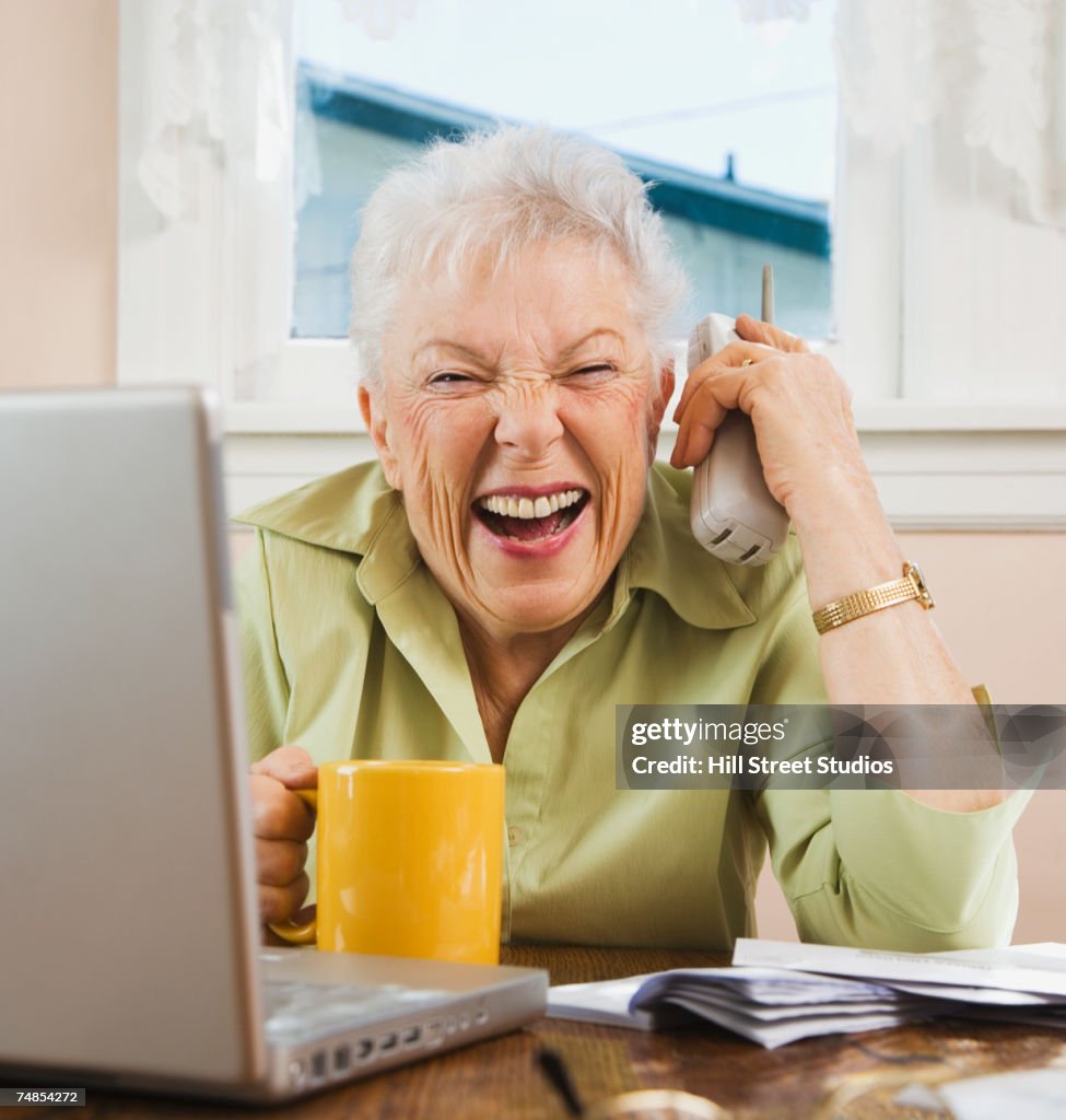 Senior woman paying bills and laughing