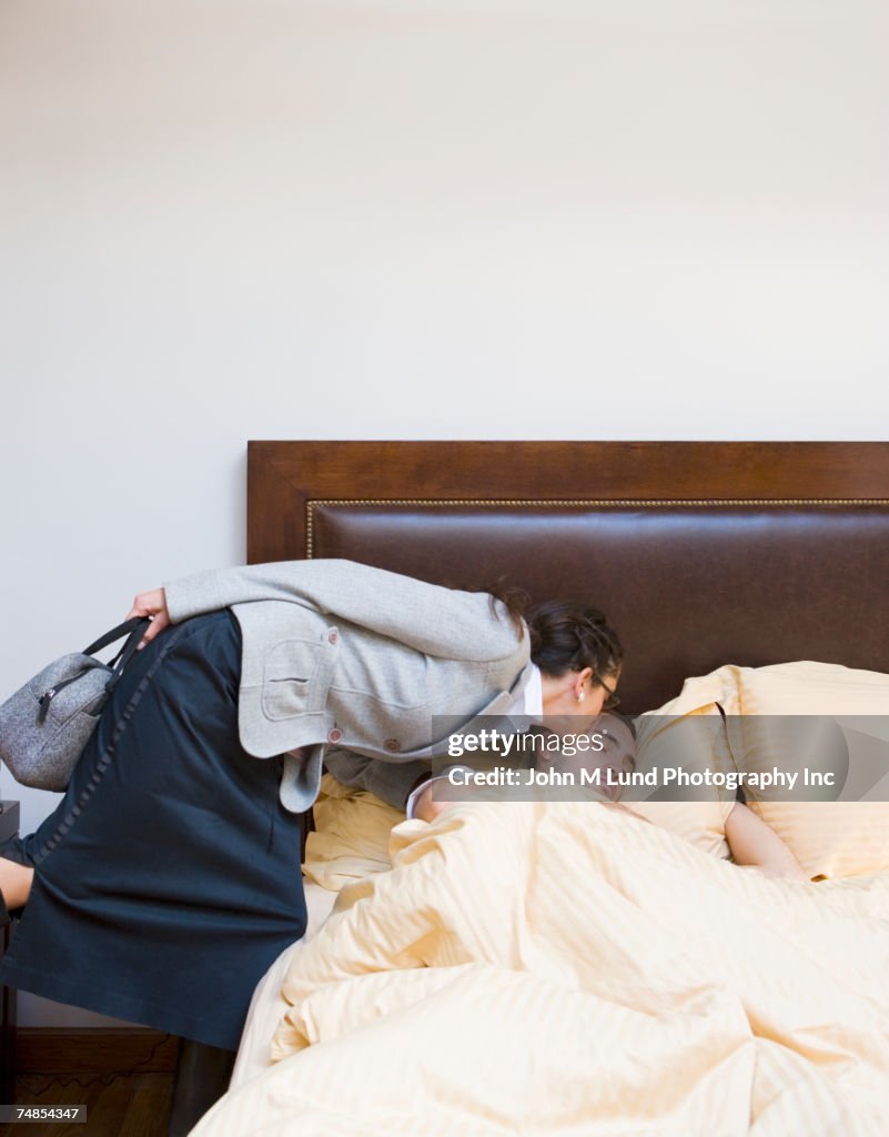 Businesswoman kissing man goodbye in bed