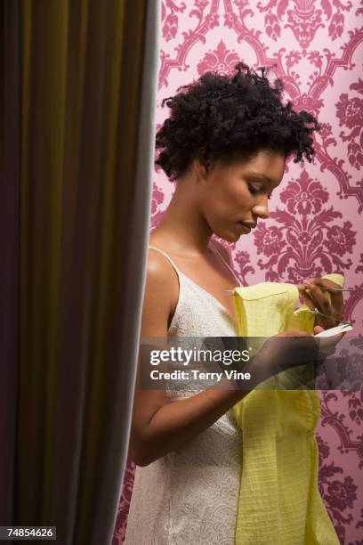 african woman looking at price tag on dress in fitting room - fitting room door stock pictures, royalty-free photos & images