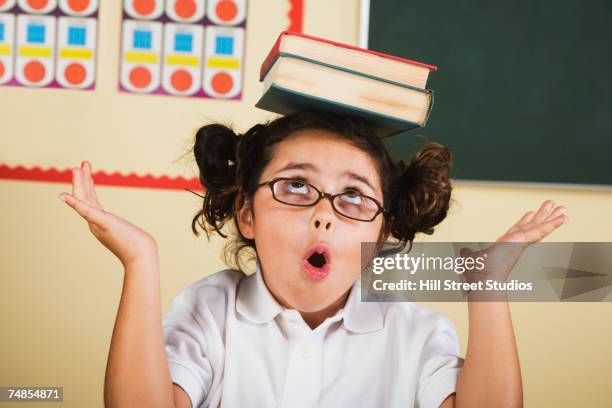 hispanic girl balancing school books on head - carrying on head stockfoto's en -beelden