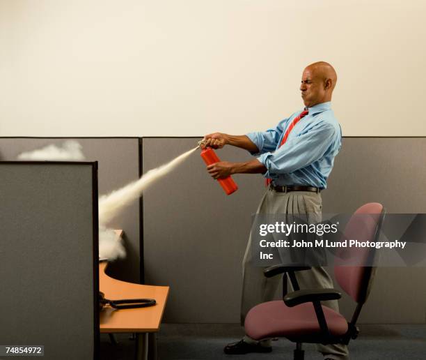 business man using fire extinguisher on computer in cubicle - stressed funny stock pictures, royalty-free photos & images