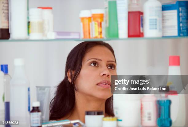 hispanic woman looking in medicine cabinet - armário de banheiro - fotografias e filmes do acervo