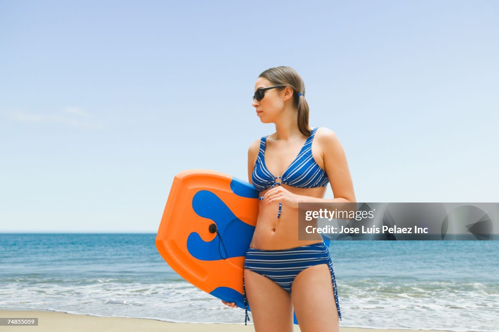 Woman holding boogie board at beach