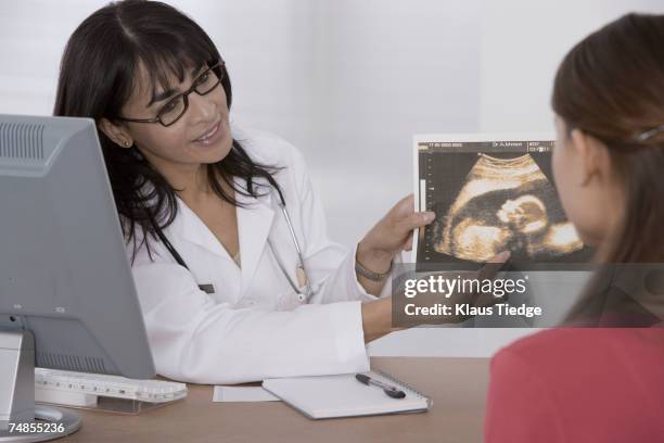 female doctor showing sonogram to patient - fetus stock-fotos und bilder