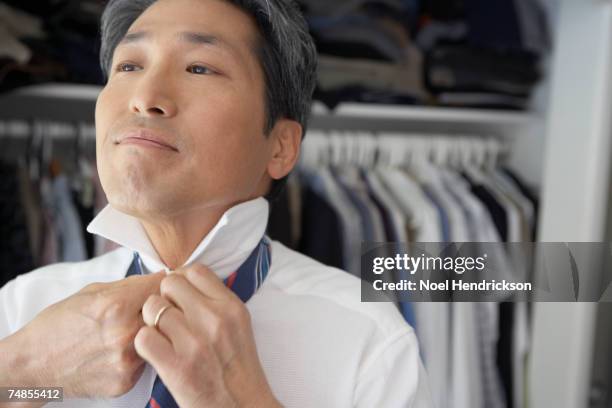 asian businessman putting on tie - get dressed male stock pictures, royalty-free photos & images