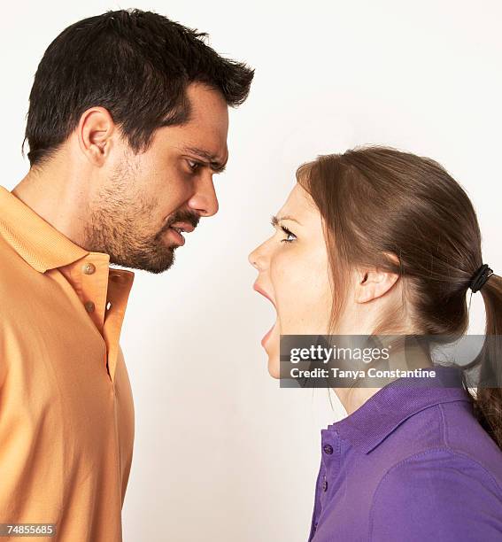 mixed race woman yelling at boyfriend - mixed race man standing studio stockfoto's en -beelden