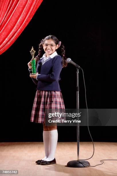 hispanic girl holding trophy on stage - spelling bee stock pictures, royalty-free photos & images