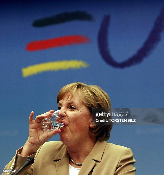 German Chancellor Angela Merkel drinks a glass of water while addressing a press conference at the end of the first day of the European Union summit...