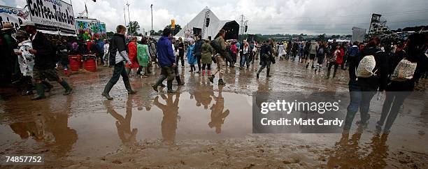 Music fans in wellies walk in the mud as they wait for a band on the Pyramid Stage, Adjegas, open the festival at Worthy Farm, Pilton near...