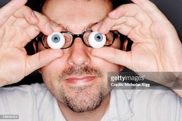 man holding glass eye balls, close-up - occhio di vetro foto e immagini stock