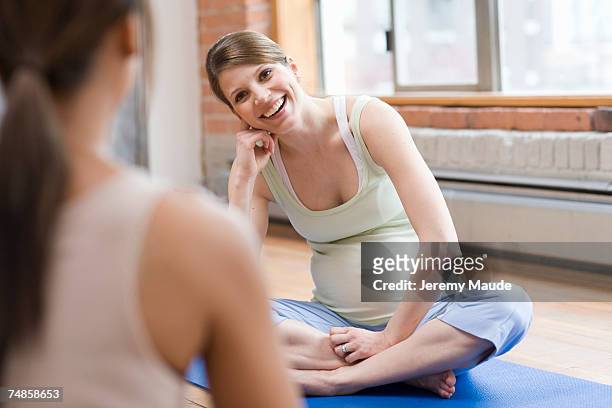 pregnant woman looking to yoga instructor, smiling - prenatal care stock pictures, royalty-free photos & images